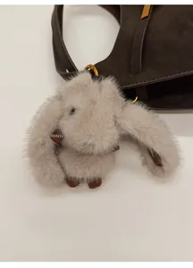 Dettaglio di un ciondolo a forma di coniglio grigio con anello d'oro su borsa in pelle