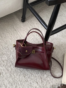 Retro burgundy matte leather tote bag with metal lock and matching mini pouch on a rug