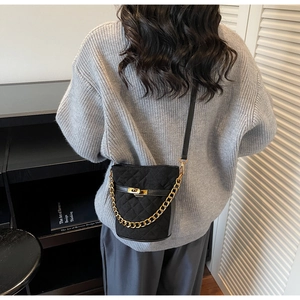 Sac seau matelassé noir avec chaîne dorée porté en bandoulière pour un look chic
