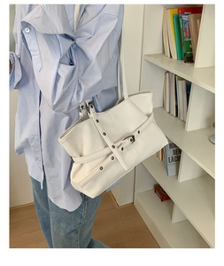 Detail view of the white lychee grain texture and metal buckle on this large tote bag