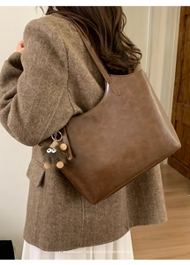 Brown vintage faux leather tote bag with a small plush monster charm accessory