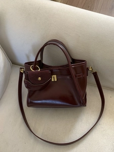 Retro burgundy leather tote bag with small charm purse and gold hardware on white sofa