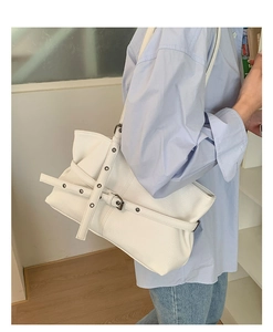 Close-up of white pebble leather tote bag featuring metal eyelets and belt buckle details