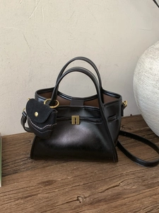 Minimalist black faux leather tote bag with gold geometric buckle and mini pouch charm