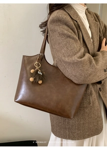 Detailed texture of dark brown PU leather tote bag featuring a cute plush monster charm