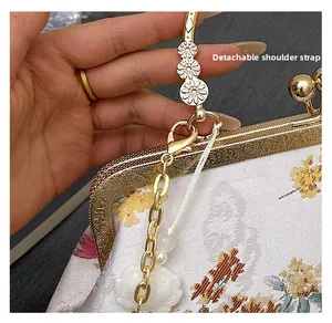 Detail of embroidered floral pattern on white satin clutch with gold metal frame