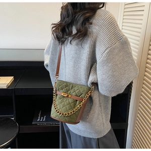 Détail du sac seau matelassé vert olive avec chaîne dorée et bandoulière en cuir