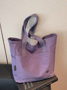 Minimalist purple canvas tote bag with shoulder straps and woven label detail