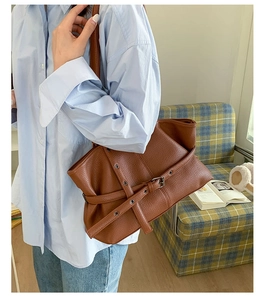 Detail of dark brown tote bag with metal grommets and lychee grain leather texture