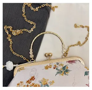 Detail of vintage floral embroidery with golden handle and decorative jade-style pendant