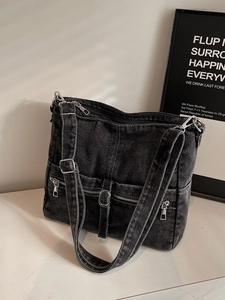 Grey denim tote bag with multiple zipper pockets and adjustable silver buckles in soft light