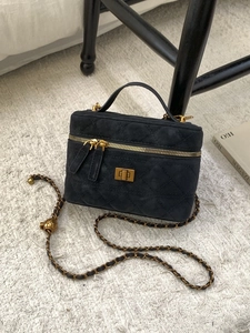 Elegant black quilted crossbody bag with gold hardware on a textured white carpet
