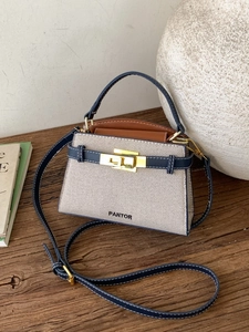 Navy and beige woven handbag with gold clasp and leather strap in minimalist setting
