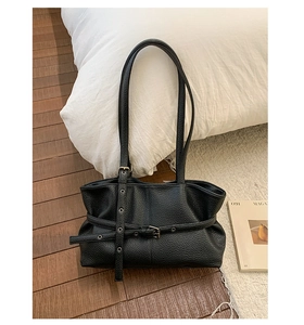 Close-up of black lychee-grain leather tote bag with silver eyelets and buckle detail