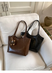 Close-up of retro matte leather tote bags in dark brown and black with plush charms