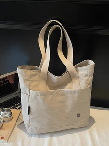 Minimalist beige canvas tote bag with large front pocket and laptop office accessories