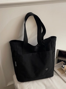 Minimalist black tote bag in durable nylon with spacious front pocket and woven label