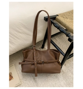 Close-up of brown litchi pattern leather shoulder bag with decorative buckle strap detail