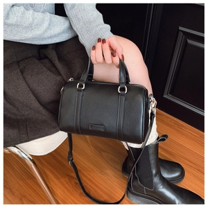 Detail of black pebbled leather Boston bag with dual handles and brand label on front