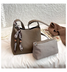 Detail of dark brown leather bucket bag with silk scarf on handle and canvas pouch