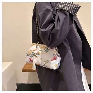 Close-up of vintage style white silk clutch bag with floral embroidery and golden handle