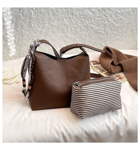 Detail of dark brown pebble leather handbag set with printed silk scarf handle decoration