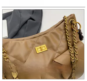 Close-up of brown quilted leather shoulder bag with gold chain strap and square metal lock