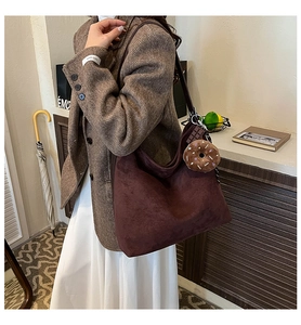 Detail of dark brown suede hobo bag with unique chocolate bar and donut plush charms