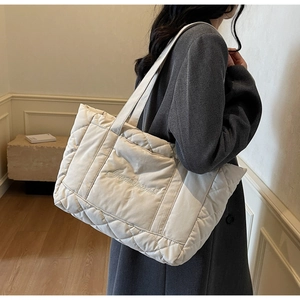 Detail of off-white quilted tote bag featuring elegant letter embroidery and rhombus pattern