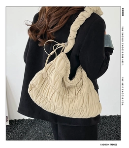 Detail of beige quilted hobo bag with pleated texture and adjustable wide shoulder strap