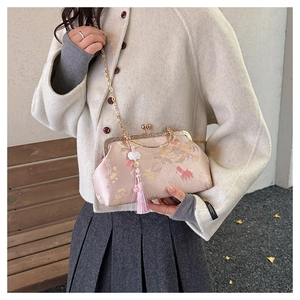 Detail of pink embroidered shell bag with floral patterns, gold frame, and silk tassels