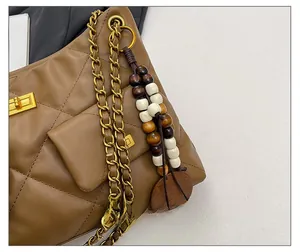 Detail of brown quilted leather bag with gold chain strap and vintage beaded charm