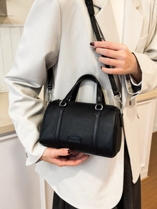 Classic black litchi pattern Boston bag with top handles and shoulder strap shown on model