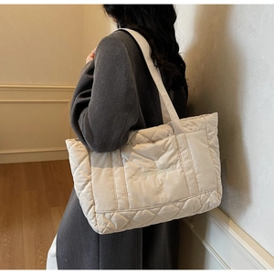 Detail view of large quilted tote bag in creamy white nylon featuring stylish embroidery