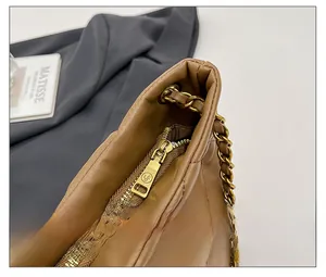 Detail of smooth gold zipper and chain strap on quilted vintage shoulder bag
