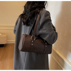 Detail of dark brown matte leather bucket bag with silver rings and long shoulder straps