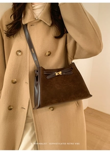 Detail of vintage matte coffee bucket bag with gold twist lock on beige wool coat