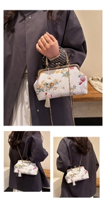 Detail of floral embroidery vintage clutch bag with gold handle and silk tassel accent