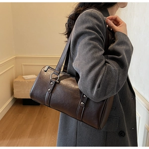 Detail of dark brown leather cylinder shoulder bag with silver hardware and dual straps