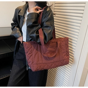 Close-up of quilted tote bag in wine red featuring letter embroidery on shoulder strap