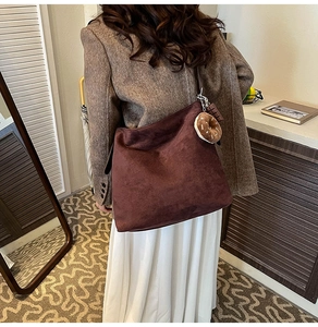 Detail of a large brown suede hobo bag with a stylish donut-shaped bag charm accessory