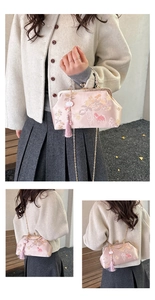 Detail of pink silk clutch with floral embroidery, metal clasp and tassels