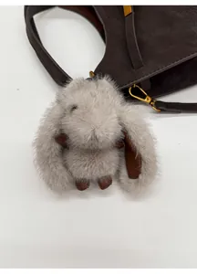 Detailed view of a soft grey plush rabbit keychain charm on a dark brown bucket bag