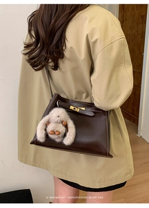 Detail of retro dark brown leather bucket bag with gold lock and plush rabbit charm