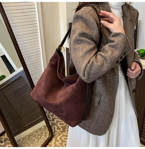 Close-up of a burgundy suede hobo bag with adjustable brown leather shoulder strap