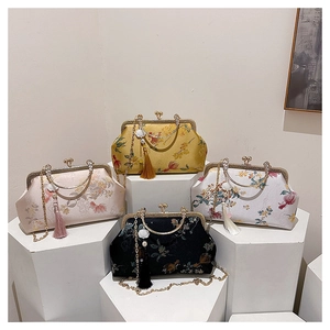 Detail van vier geborduurde zijden clutches met kwastjes in geel, roze, wit en zwart