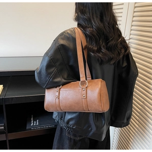 Close-up of brown wax leather pillow bag with silver ring hardware and sturdy rivets