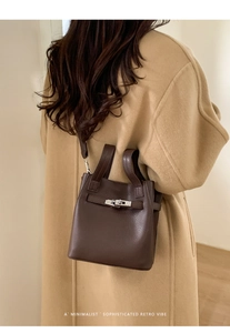 Close-up of retro dark brown lychee grain leather handbag with silver lock detail