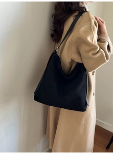Detail of a large black hobo shoulder bag worn with a wool coat for a chic winter look
