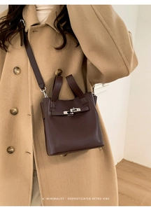 Detailed side view of a brown pebbled leather bucket bag with silver twist lock and strap